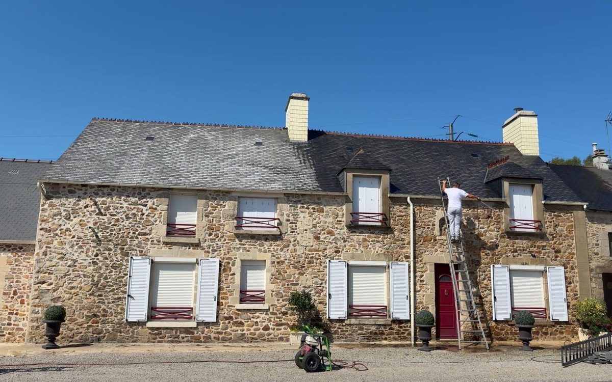 Toiture en ardoise d'une longère en pierre en cours de nettoyage haute pression